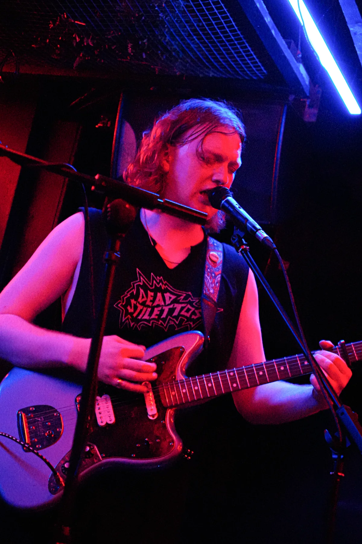 Jem smiling while singing and playing guitar live