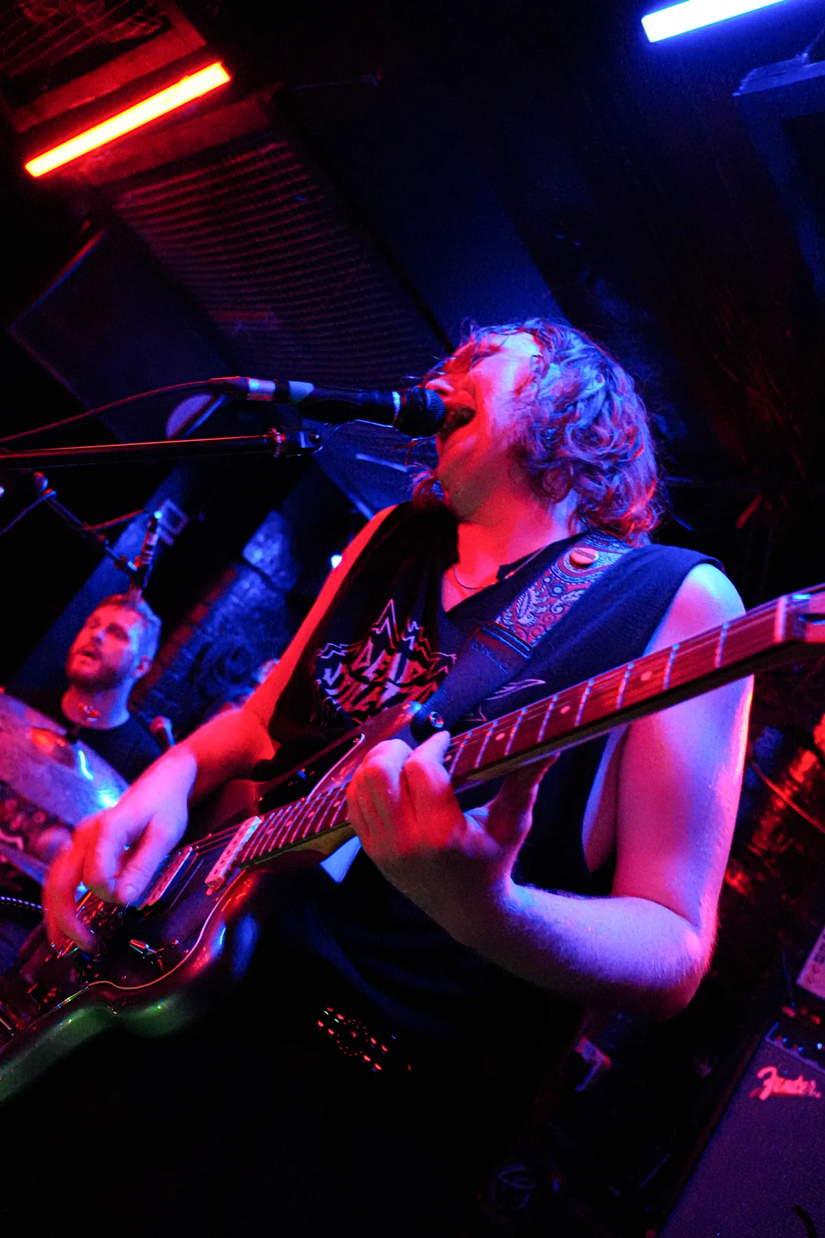 Jem playing guitar with Farris visible behind the drum kit